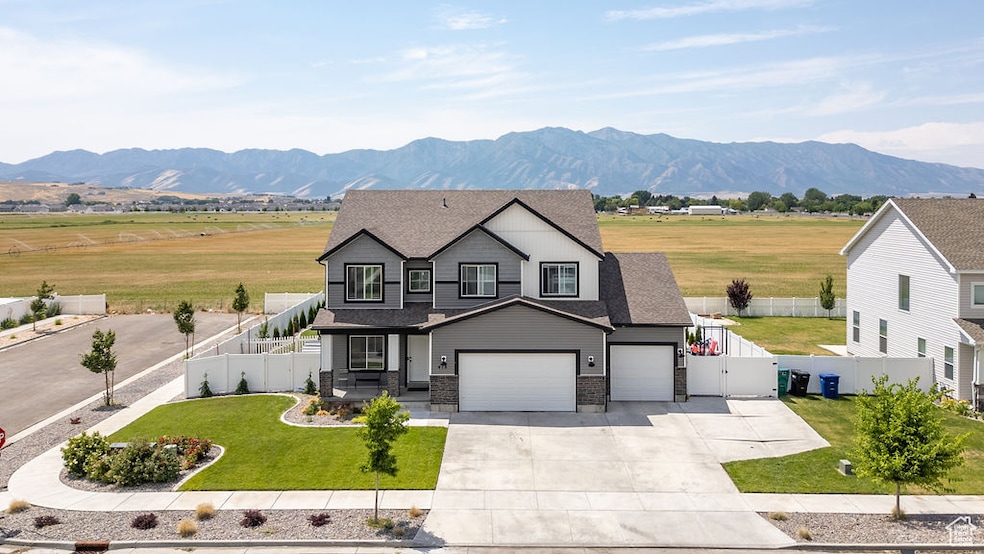 View of front of property with driveway, a mountain view, a shingled roof, a gate, and a garage