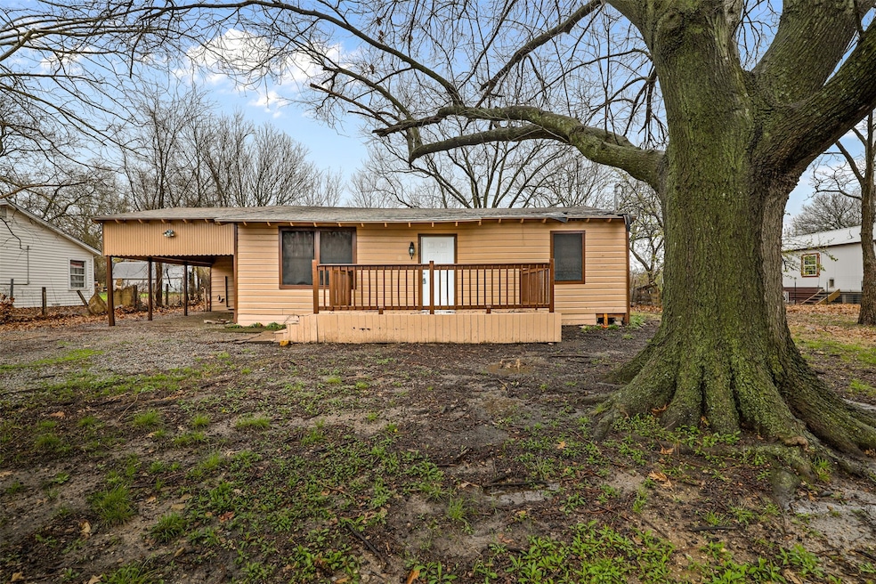 Rear view of house featuring a wooden deck and a carport