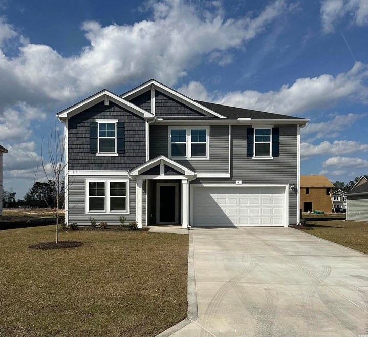 View of front of house featuring driveway, an atta