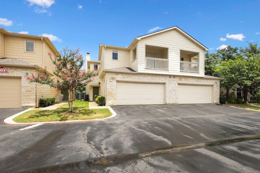 Traditional-style home featuring stone siding, a balcony, driveway, and a garage