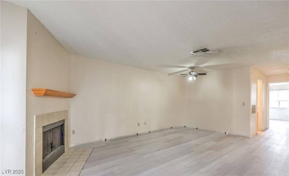 Unfurnished living room with a tiled fireplace, li