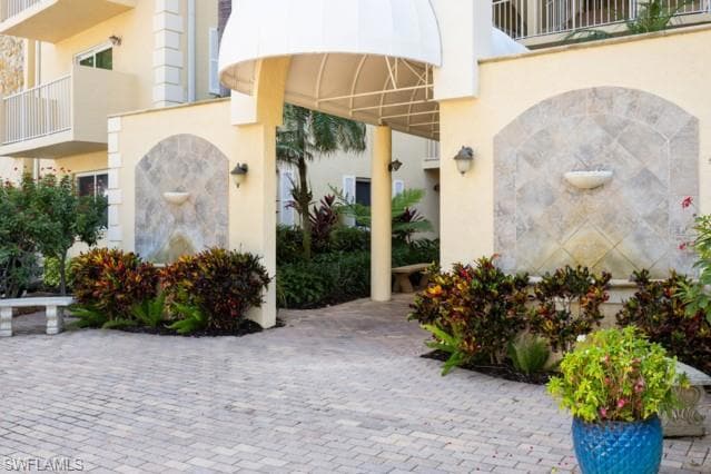 Doorway to property featuring stucco siding and a balcony