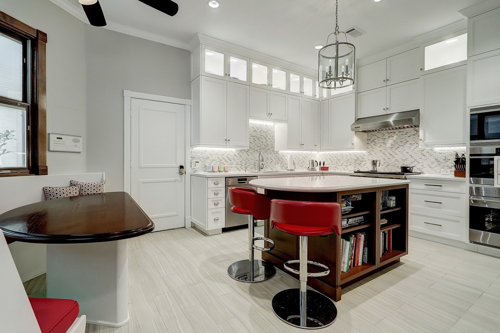 Large Kitchen with island. Great built-in breakfast nook. Double ovens with above counter microwave. Custom lighting, Wolf Cooktop, Sub zero fridge. Note the custom shelves for cook books. Intercom control panel with radio