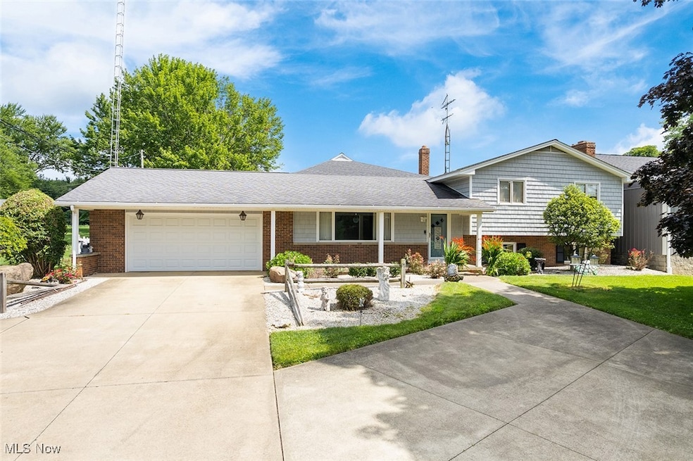 Tri-level home featuring an attached garage, a chimney, concrete driveway, and brick siding