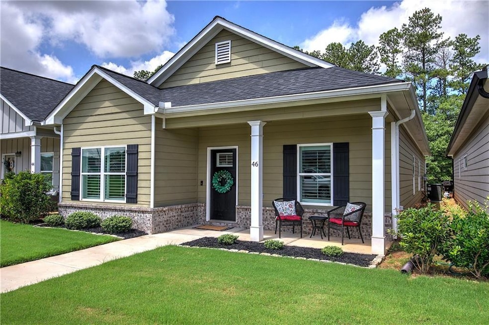 View of front of home with a front yard, covered porch, a shingled roof, brick siding, and board and batten siding