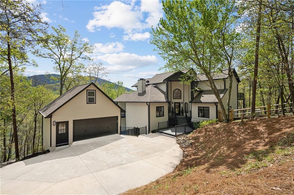 View of front of house featuring roof with shingles, an outdoor structure, a chimney, driveway, and fence