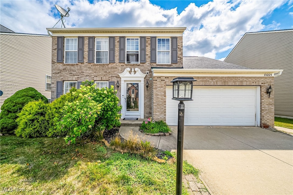 Colonial inspired home featuring brick siding, concrete driveway, a garage, and a front lawn