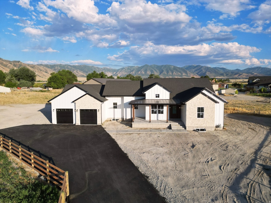 Modern inspired farmhouse featuring a mountain view, a standing seam roof, a porch, a metal roof, and asphalt driveway