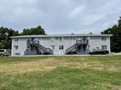 Rear view of house featuring a yard and stairway