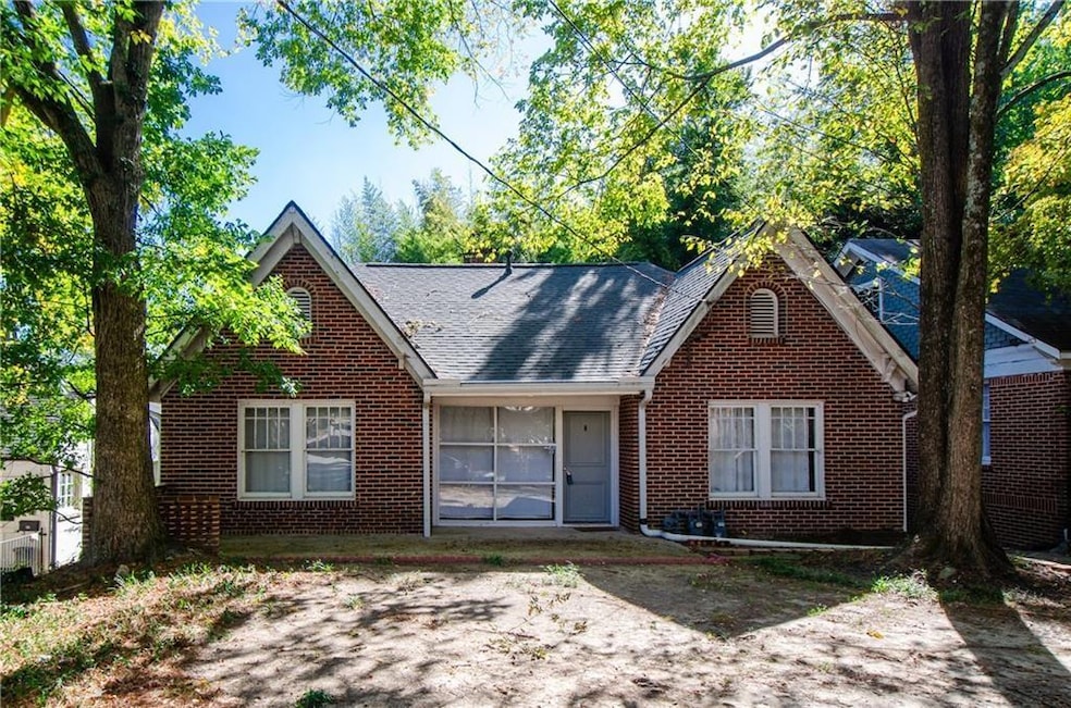 View of front of home with brick siding, a shingled roof, and covered porch