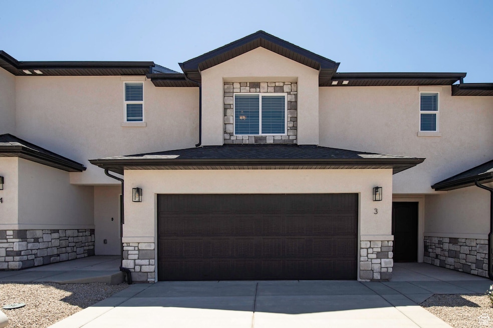 View of front of property with stone siding, stucco siding, driveway, and a garage