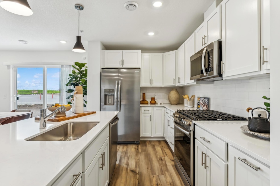 (Photo of a model home, actual homes finishes will vary) The beautiful kitchen has sleek white cabinets, SS finish appliances, luxury vinyl planking, tons of lighting and natural light as well as an island.