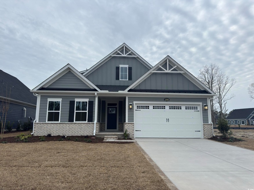 Craftsman-style home with board and batten siding, an attached garage, brick siding, and driveway