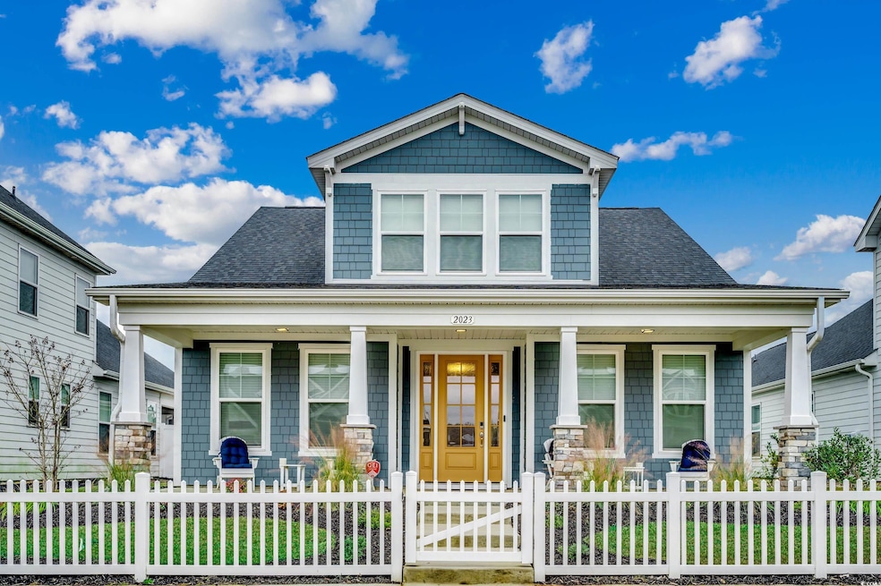 View of front of house featuring a porch, a fenced front yard, and roof with shingles
