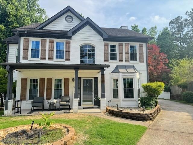 View of front facade featuring covered porch and brick siding