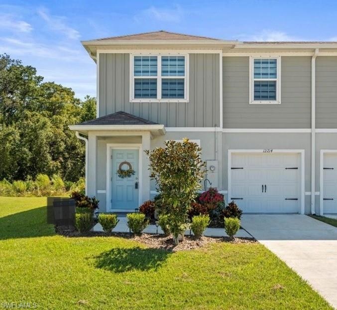 View of front of property featuring board and batten siding, a front lawn, driveway, and a garage