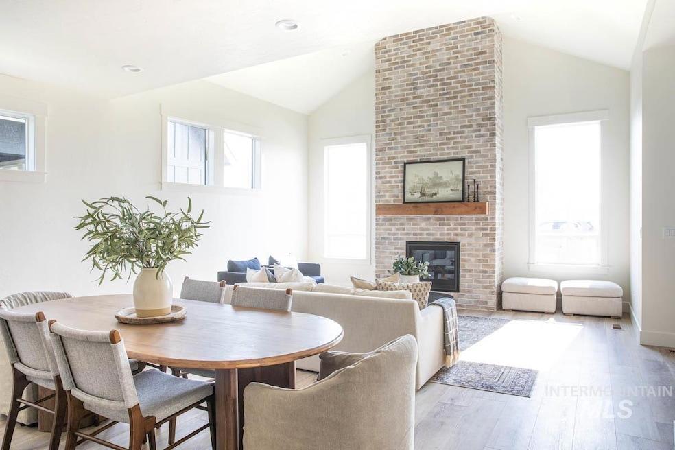 Dining room with a brick fireplace, wood finished floors, and vaulted ceiling