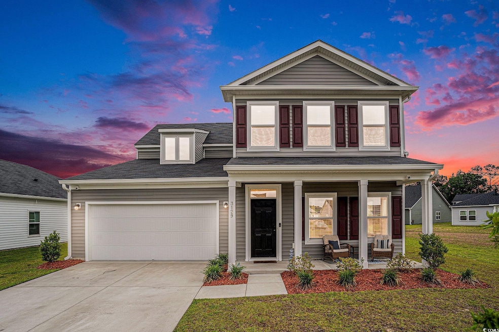 Traditional home featuring covered porch, driveway, an attached garage, a front lawn, and roof with shingles