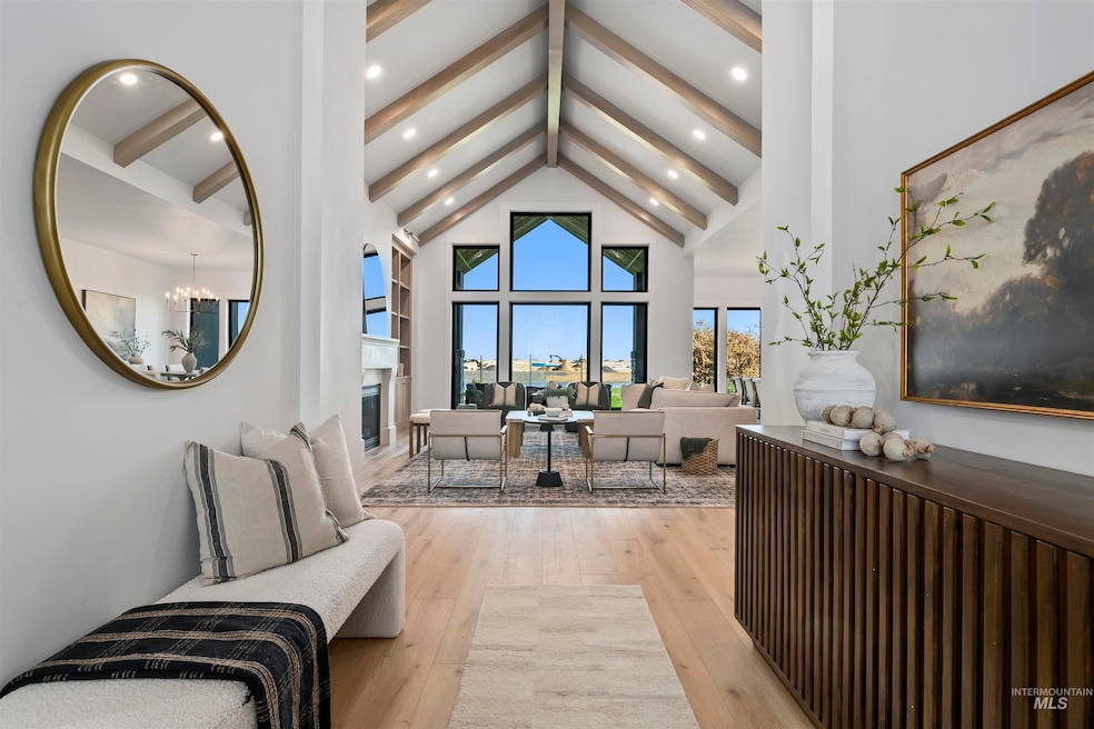 Living room with beamed ceiling, light wood-style flooring, high vaulted ceiling, a fireplace, and a chandelier