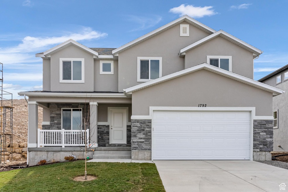View of front of home featuring stone siding, covered porch, stucco siding, and driveway