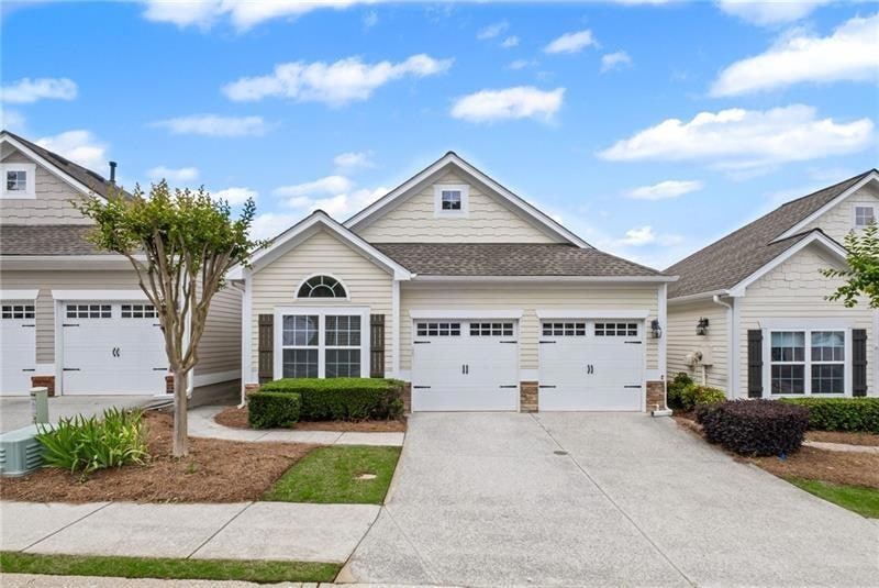 Craftsman-style house featuring roof with shingles, driveway, an attached garage, and stone siding