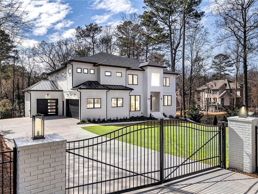 Contemporary house with concrete driveway, a standing seam roof, a gate, and a fenced front yard