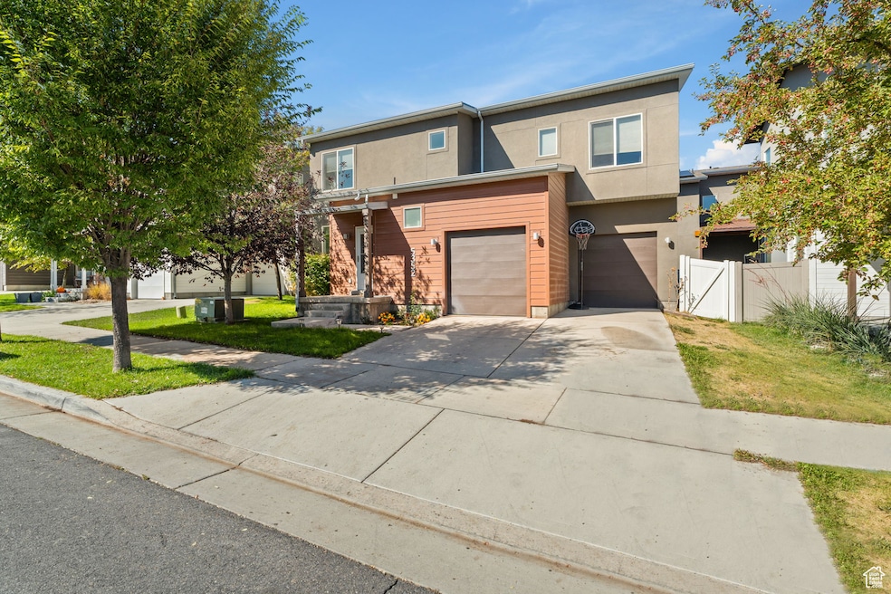Traditional-style house featuring concrete driveway, an attached garage, stucco siding, and a gate