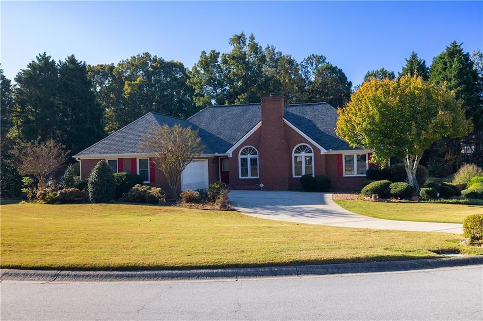 Ranch-style home with driveway, a front lawn, a chimney, and brick siding