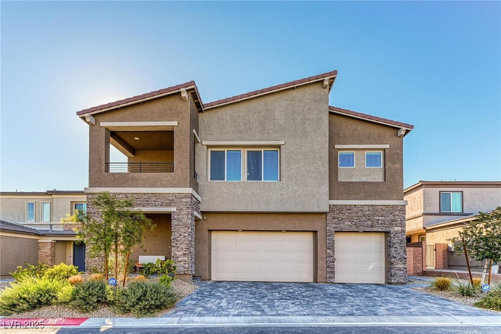View of front of home featuring stone siding, a balcony, a garage, and stucco siding
