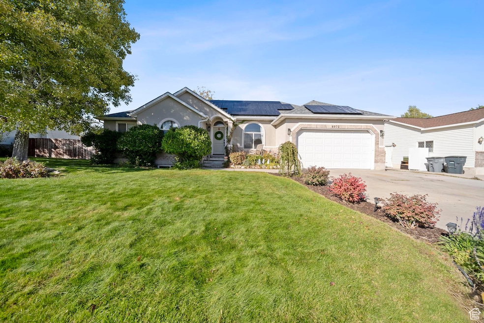 Single story home with solar panels, concrete driveway, a front lawn, and an attached garage