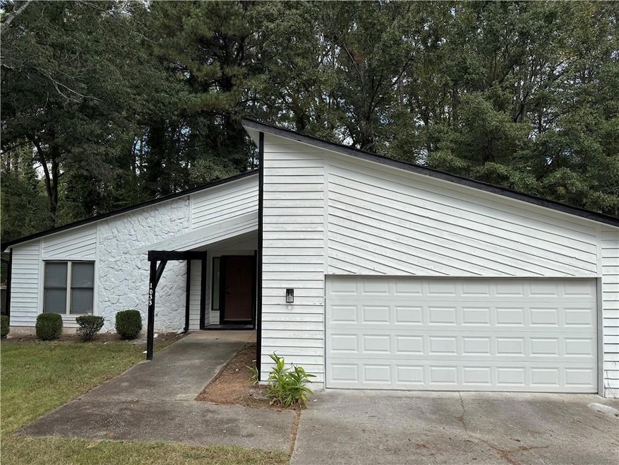 Mid-century modern home with concrete driveway and view of wooded area