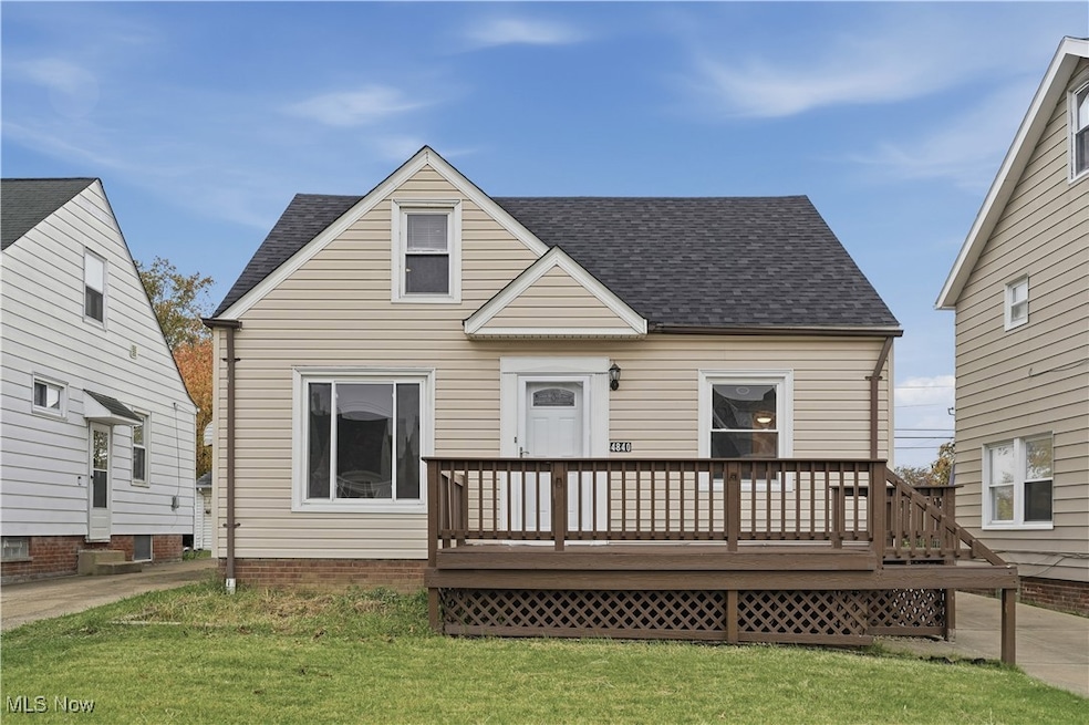 View of front of house featuring roof with shingles, a deck, and a front lawn