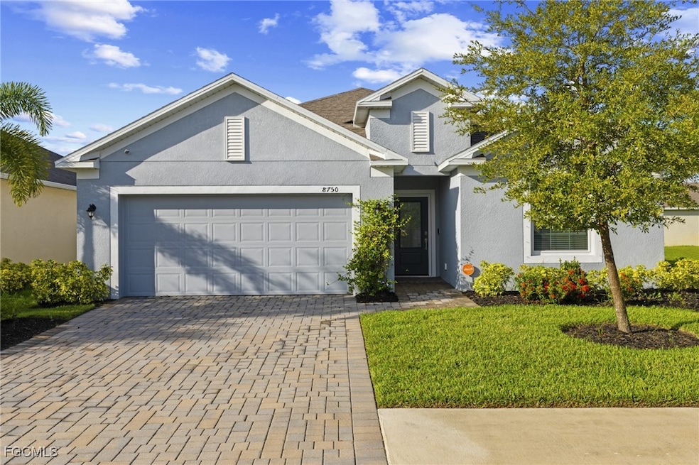 View of front facade featuring decorative driveway, stucco siding, a garage, and a front yard