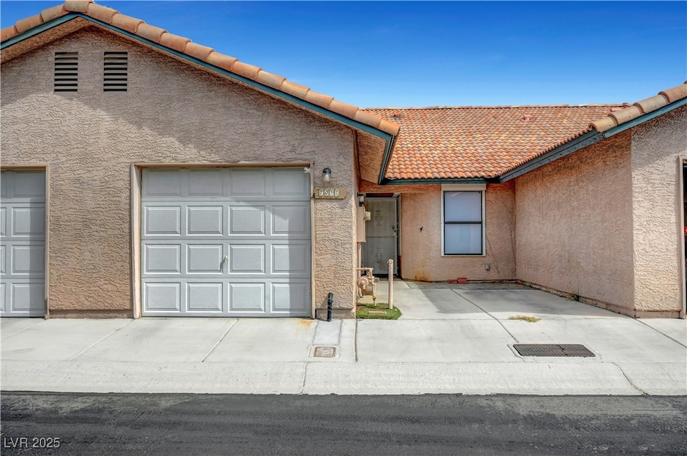 View of front of house featuring a tile roof, stucco siding, an attached garage, and driveway