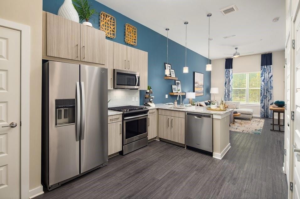 Kitchen featuring stainless steel appliances, light brown cabinetry, pendant lighting, a peninsula, and tasteful backsplash