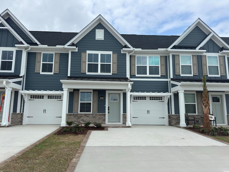 View of front of house with driveway, metal roof, 