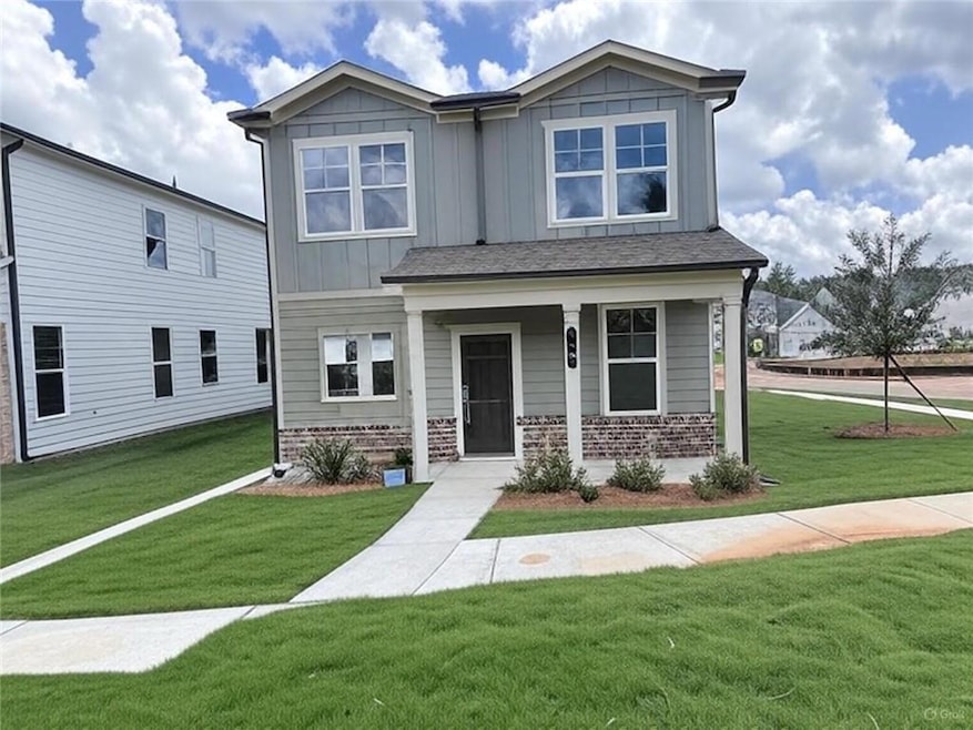 Townhome / multi-family property featuring a front lawn, board and batten siding, covered porch, and brick siding