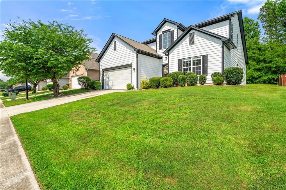 View of front facade featuring driveway, a front lawn, and a garage