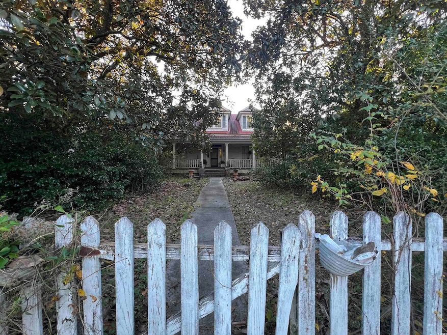 View of property hidden behind natural elements featuring covered porch