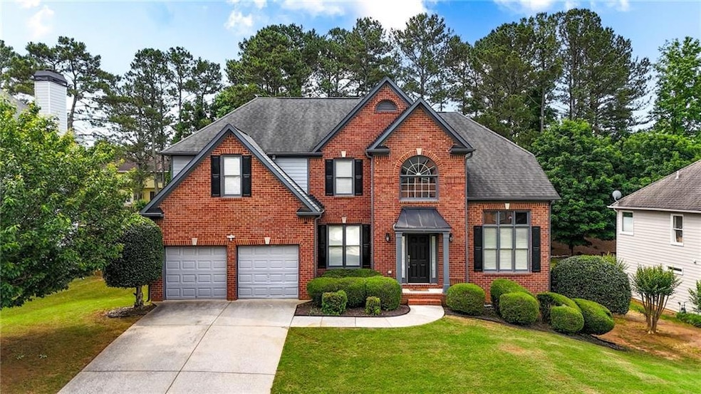 Traditional home with concrete driveway, brick siding, an attached garage, a front lawn, and roof with shingles