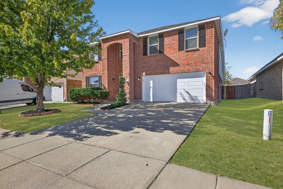 View of front of home with concrete driveway, brick siding, a front yard, and an attached garage