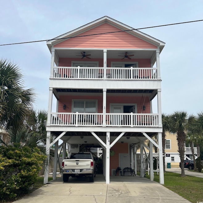 Beach home featuring a ceiling fan, a carport, driveway, and a balcony