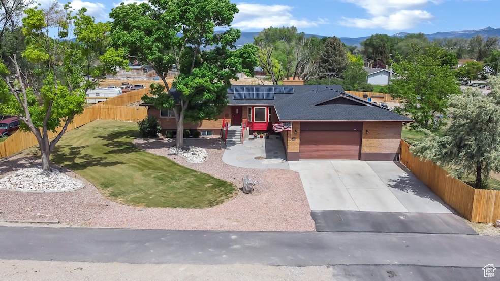 View of front of house with roof with shingles, solar panels, brick siding, driveway, and an attached garage