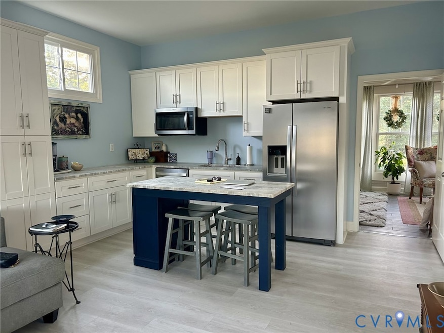 Kitchen with a kitchen breakfast bar, stainless steel appliances, plenty of natural light, and white cabinets