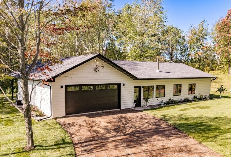 Single story home with driveway, an attached garage, and a front lawn