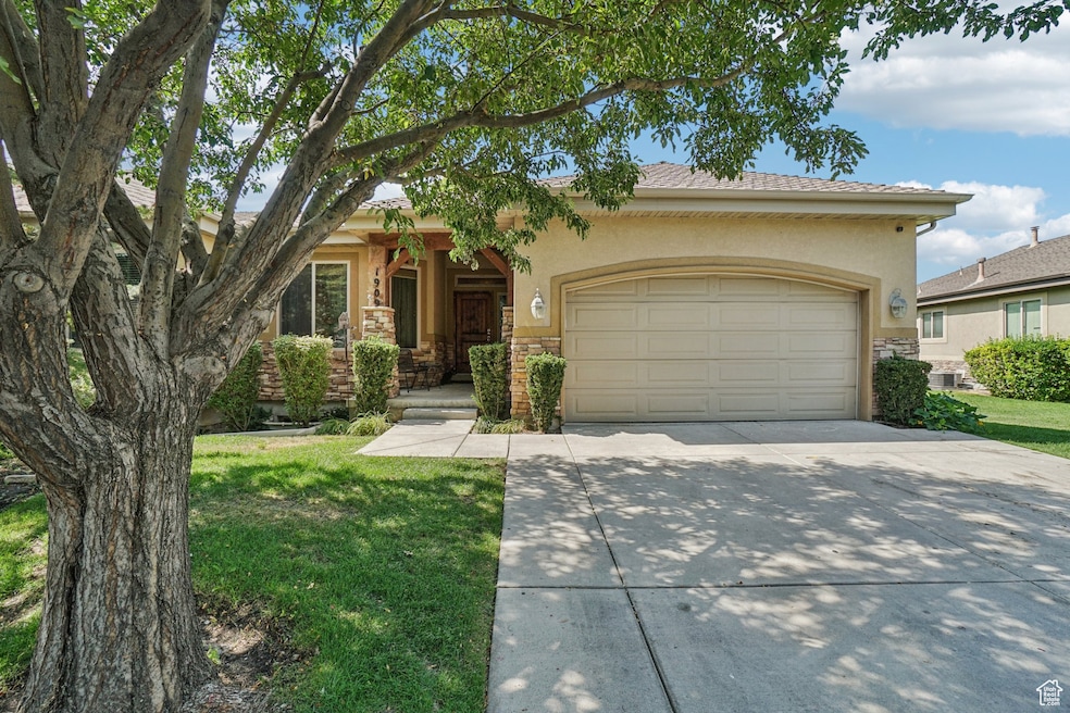 View of front of property with a garage, stone siding, stucco siding, and driveway