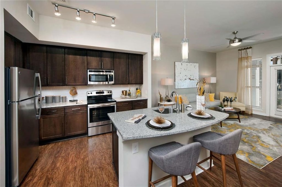 Kitchen with ceiling fan, stainless steel appliances, sink, dark hardwood / wood-style floors, and track lighting