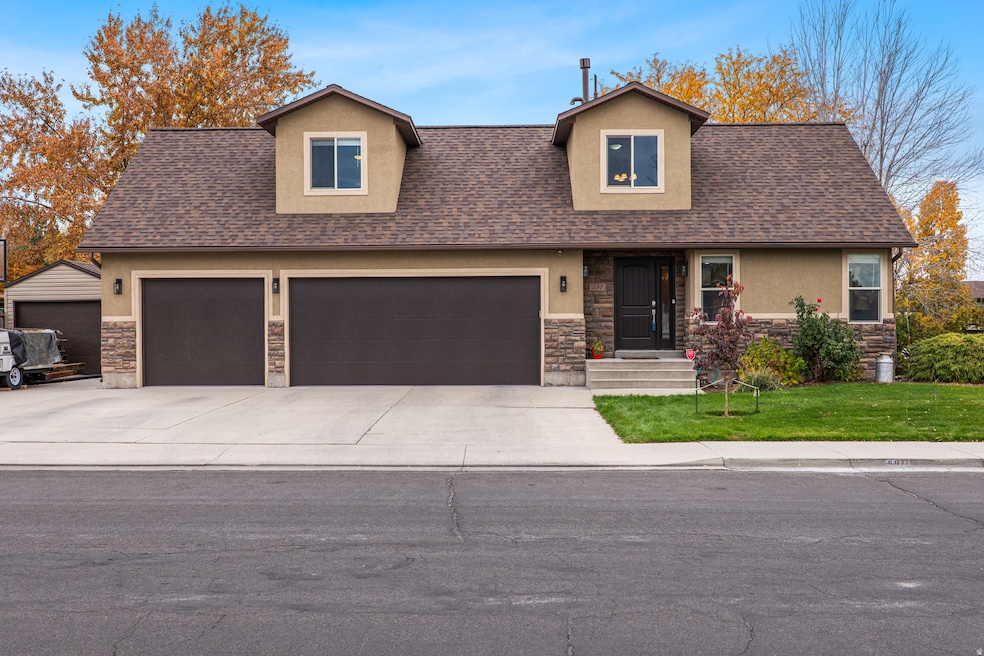 View of front of property featuring stone siding, a shingled roof, a front lawn, stucco siding, and driveway