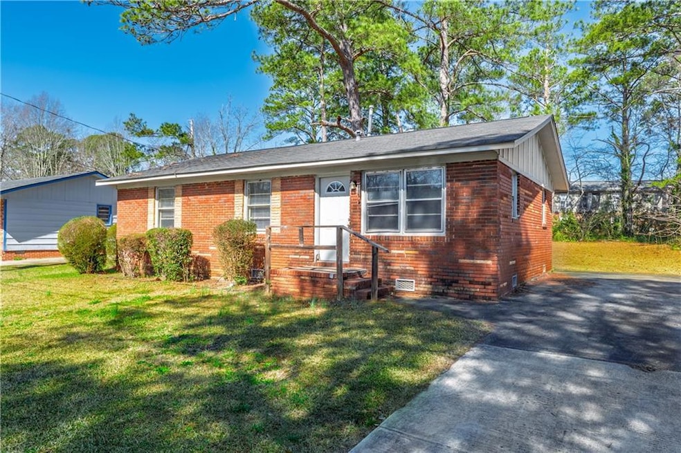 View of front of home with a front yard, brick siding, and crawl space