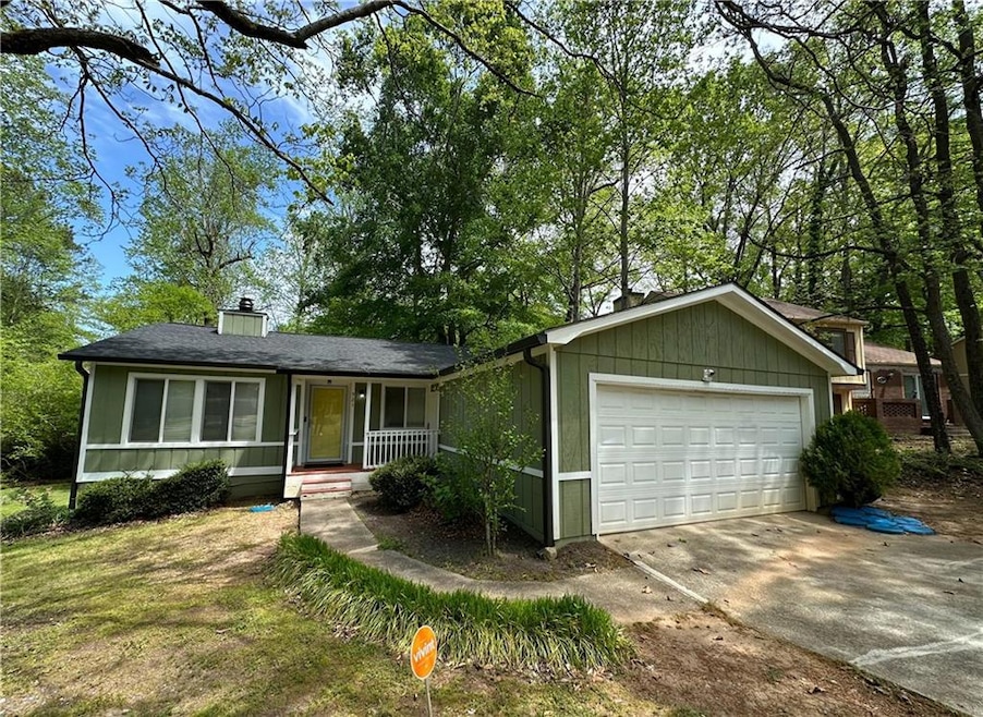 Ranch-style house featuring a chimney, driveway, covered porch, and an attached garage